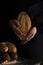 Baker woman holding rustic organic loaf of bread in hands - rural bakery. Natural light, moody still life.