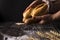 Baker woman holding rustic organic loaf of bread in hands - rural bakery. Natural light, moody still life.