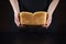 Baker woman holds warm homemade bread on a black background