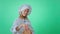 Baker woman in a uniform have a good time in a green studio playing with a fresh pretzel in front of the camera and