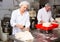 Bakers portioning dough with bench cutter at bakery