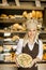 Bakery female worker posing with pizza in bakery