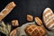 Bakery - gold rustic crusty loaves of bread and buns on black chalkboard background.