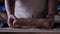 In the bakery, the hands of the baker are seen very closely as he prepares various flour products in an apron, after which he lays