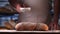 In the bakery, the hands of the baker are seen very closely as he prepares various flour products in an apron, after which he lays