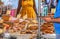 Bakery in market with focus on foreground - vendor checking phone as woman in yellow dress approaches - cropped and unrecognizable