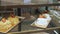 Bakery vitrine with cakes and pastries on glass shelves.