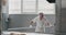 Bakery worker equipped in a white uniform take the bread from industrial oven machine using a special torch