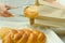 Bakery worker placing loaf of bread inside brown paper bag using large silver tweezers