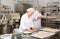 Bakery worker preparing raw baguette dough for baking