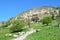 Bakhchisaray, herd of goats and sheeps grazing in the beam Maryam-Dere in sunny spring day in front of the cave town Chufut-Kale.