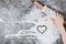 Baking background. Girl hands keep rolling pin and heart of flour on gray table with copy space, top view.