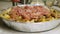 Baking dish. A woman`s hand lays out sliced raw meat on potatoes