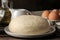 Baking ingredients. baking tools. dough closeup and butter, eggs, sugar, milk on a brown wooden background