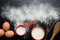 Baking ingredients on a dark, stone table: eggs, flour and milk