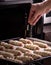 Baking oven: the baker sprinkles buns with sesame seeds before baking in the oven.