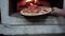 baking pizza in an open fire in a firewood oven. A female hand puts mozzarella pizza in the oven in an iron pan. Baking