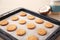 Baking tray with cookies and coconut on table