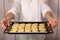 Baking tray with raw cookies heart shaped in the hands of a baker.