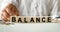 BALANCE inscription on the texture of wooden cubes. A business man holds a cube in his hand. An inscription on a financial,