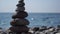 Balanced pebble pyramid on the beach on a sunny day. Abstract Sea bokeh on the background. Selective focus. Zen stones