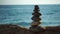 Balanced pebble pyramid on the beach on a sunny day. Abstract Sea bokeh on the background. Selective focus. Zen stones