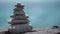 Balanced pebble pyramid on the beach on a sunny day. Abstract Sea bokeh on the background. Selective focus. Zen stones