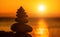 Balanced pebble pyramid silhouette on the beach. Abstract warm sunset bokeh with Sea on the background. Zen stones on the sea