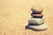 Balanced stacked pebble stones on sand background.