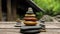 Balanced Stone Stacks on Wooden Surface in Serene Outdoor Setting. Three towers of smoothly rounded multicolored stones balance