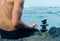 Balancing stones arranged in a pyramid shape with a back of a shirtless man meditating