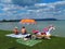 BALATONMÃ¡RIAFÃ¼RDÅ‘, HUNGARY - Jul 17, 2020: Holiday couple sitting under colorful sunshade parasol on the beach of lake Balaton