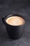 Balck ceramic mug of fresh hot coffee on on dark stone background. Vertical