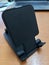 Balck Standing Folding Smart Phone On Brown Wood Texture Office Desk