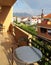 Balcony with gray table and bronze chairs in the house. Rainbow over the mountain and white houses with red