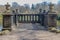 Balcony or observation deck with fence and decorative stone ornaments above a fountain by a lake surrounded by bare trees