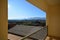 Balcony. Panoramic view of the city center with sun, cold front clouds and protection grid in the foreground