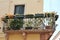 balcony on a typical Italian tenement house, old balcony decorated with pots of flowers, wooden shutters