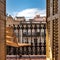 Balcony with a wrought iron railing, wooden sashes and wicker chair. Sunny day with blue sky. Barcelona, Spain.