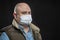 Bald adult man in a medical mask. Black background. Precautions during the coronavirus pandemic. Close-up. Stay at home