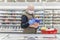 A bald adult man in a medical mask and gloves chooses frozen foods in a supermarket. Self-isolation and precautions during the