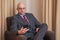 Bald attractive business man sitting in a chair in a hotel room.