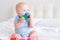 bald baby boy 3 months in blue bodysuit playing with children wooden cubes toys on bed