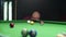 Bald bearded caucasian man with the cue at the billiard table thoroughly choosing position to make a hit. Billiard