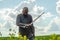 Bald bearded man in  metal chain mail over  linen shirt stands in the middle of  field, holding a sword. Militant look. Blurred