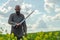 Bald bearded man in  metal chain mail over  linen shirt stands in the middle of  field, holding a sword. Militant look. Blurred