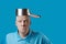 A bald brutal man in blue t-shirt put a pot on his head