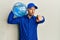 Bald courier man with beard holding a gallon bottle of water for delivery pointing with finger to the camera and to you, confident