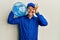 Bald courier man with beard holding a gallon bottle of water for delivery smiling happy doing ok sign with hand on eye looking