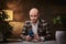 Bald european well-dressed chatting businessman sitting in the office at a table with smartphone, wearing stylish jacket